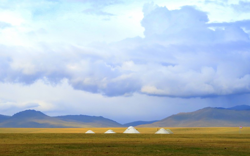 10 Kyrgyzstan Travel Tips for Adventurous Travellers with rugged scenery and yurts in the background 