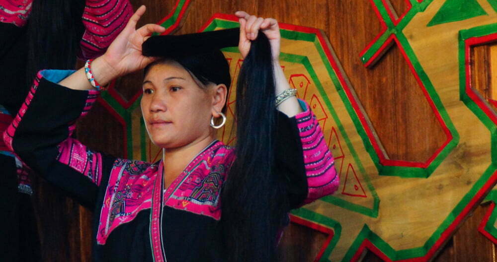 Lady wrapping her hair around her head while visiting the Red Yao Hill Tribe in China 