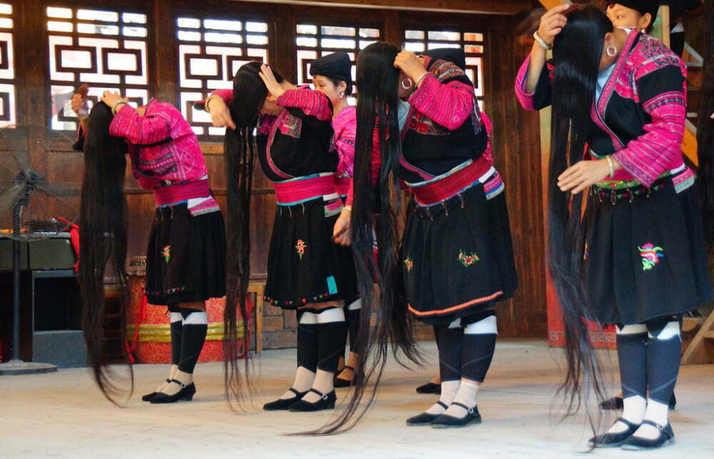 The Women With The Longest Hair In China showing us the complete length of their hair by putting in front of their faces 