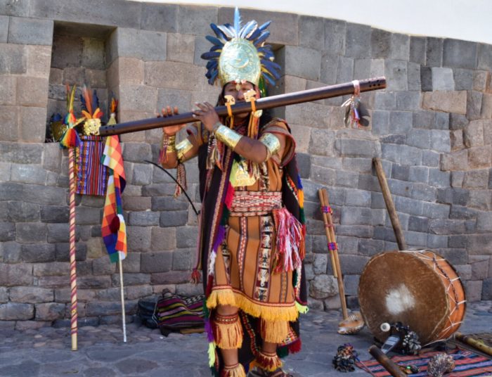Cusco man dressed in traditional clothes playing music for tourists in Peru