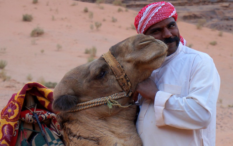 A Bedouin guide kissing his camel in Wadi Rum, Jordan with both looking very photogenic and cute at the same time 