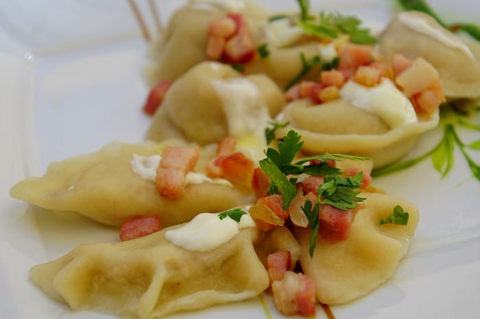A plate full of pierogi in Warsaw macro details with ingredients and sour cream layered on top with garnish in Poland A plate full of pierogi in Warsaw macro details with ingredients and sour cream layered on top with garnish in Poland