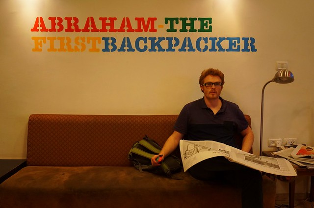 Abraham Hostel Jerusalem: Where Everyone is Welcome in Israel! Nomadic Samuel enjoying the common area couch whilst reading a newspaper
