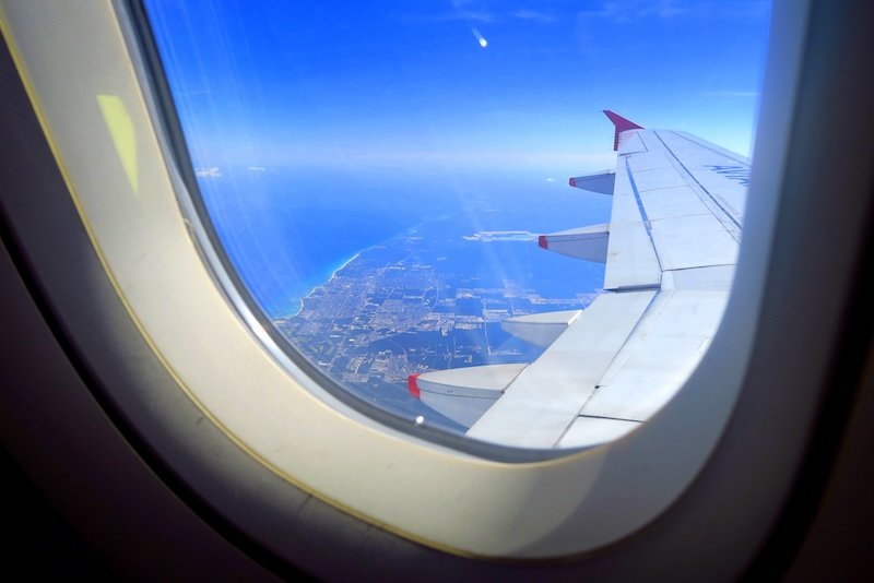 Aerial view of Mexico’s Caribbean coastline from an airplane window, with turquoise waters and the cityscape of Cancún visible below the wing under a clear blue sky Aerial view of Mexico’s Caribbean coastline from an airplane window, with turquoise waters and the cityscape of Cancún visible below the wing under a clear blue sky