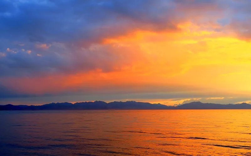 An intense fire sunset on Song Kol Lake with clouds featuring distinct colours in Kyrgyzstan 