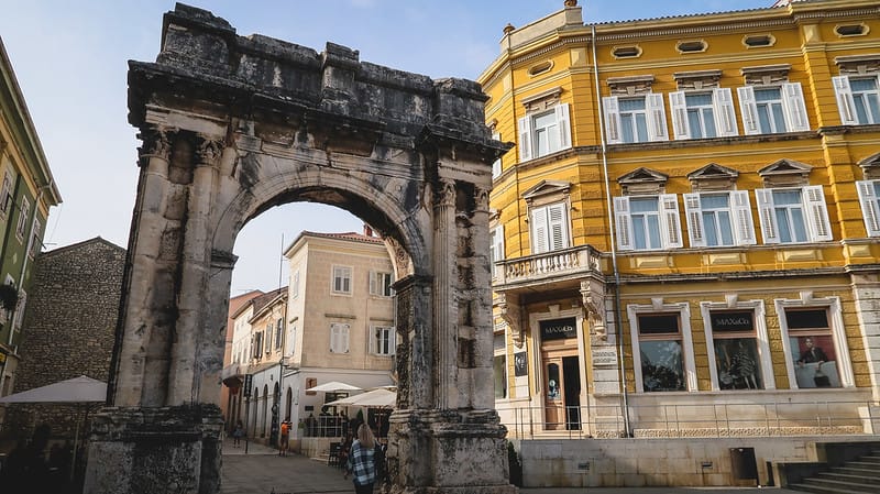 Arch of Sergii in Pula with a yellow building in the background in Croatia
