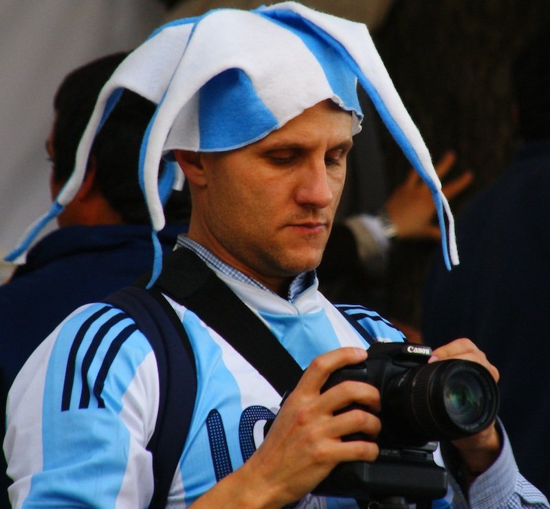 Argentina football supporter wearing jersey, joker hat and with dSLR camera in hand in Buenos Aires, Argentina 