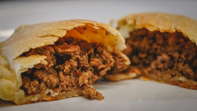 Close-up of a traditional Argentine empanada cut in half, revealing a savory minced beef filling seasoned with spices and bits of tomato. This local dish was served for lunch at Estancia San Lorenzo on Península Valdés during our day trip