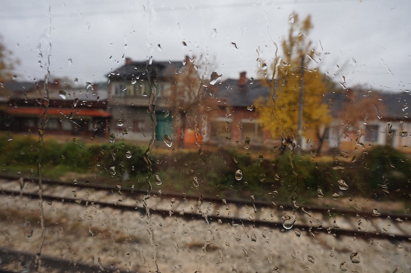 Artistic rainy weather outside of the train window in Europe with train tracks, buildings and rain droplets 