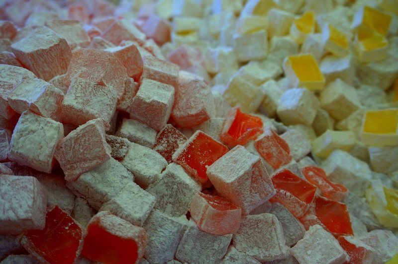 Close-up view of assorted Turkish delight cubes in soft pastel colors like rose, lemon, and orange, dusted with powdered sugar at a sweets shop in Istanbul, Turkey