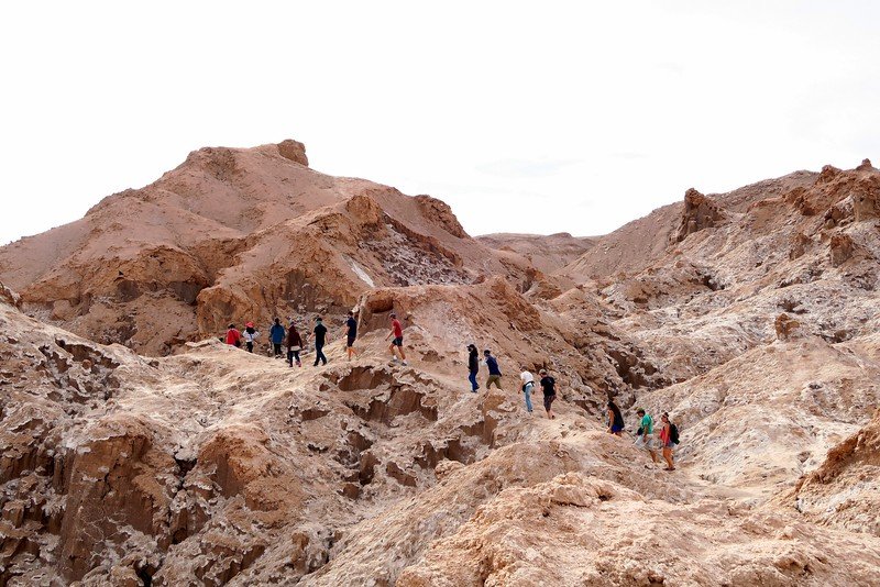 Travelers hiking across the rugged lunar-like landscapes of Valle de la Luna in Chile’s Atacama Desert