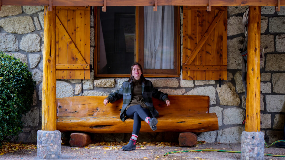 Bergner sitting on a rustic handcrafted wooden bench at Estancia Arroyo Verde, a premier fly-fishing and luxury estancia located in the Enchanted Valley of Patagonia, Argentina.
