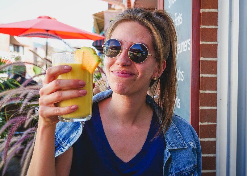 Audrey Bergner from That Backpacker enjoying a refreshing tropical fruit smoothie on the sunny patio at Le Cafetier in Sutton, Quebec during a summer getaway in the Eastern Townships