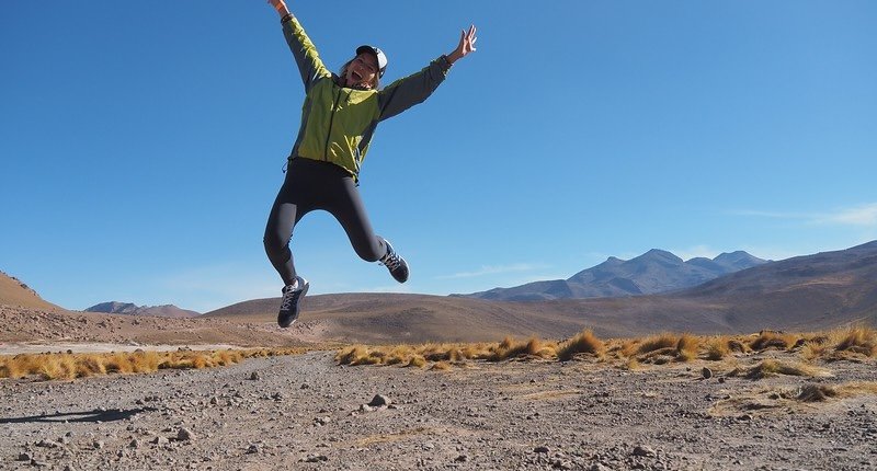 That Backpacker Audrey Bergner jumping with joy against the mountain landscapes of the Atacama Desert near El Tatio Geysers in Chile
