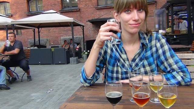 Audrey Bergner of That Backpacker enjoying a flight of beer samplers at the outdoor terrace of Hotel Katajanokka in Helsinki, Finland, a former prison turned boutique hotel, highlighting the unique dining and craft beer experiences available to guests