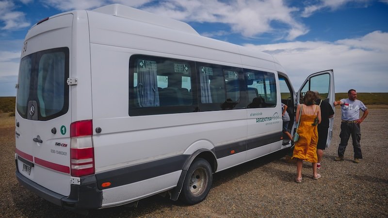 Audrey Bergner of That Backpacker boards a white tour van on a guided excursion around Península Valdés, Argentina. The scene captures the start of a day trip from Puerto Pirámides, highlighting organized transportation for exploring Patagonia’s landscapes