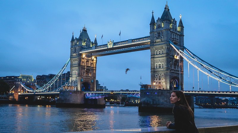 Audrey Bergner of That Backpacker enjoying the peaceful early morning view of London’s iconic Tower Bridge illuminated against the twilight sky, capturing the magic of sunrise along the River Thames during a 24-hour exploration of the city