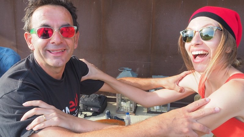 Audrey Bergner of That Backpacker laughing with friend Jaume while balancing with hands on shoulders during grape stomping at La Vinyeta winery in Costa Brava, Spain, capturing the fun and camaraderie of this traditional Catalan winemaking ritual