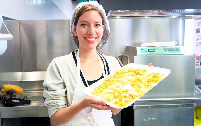 Audrey Bergner of That Backpacker holding a tray of freshly prepared handmade pasta during a cooking class at Casa Artusi in Emilia-Romagna, Italy, showcasing the region’s culinary traditions and the authentic food experiences travelers can enjoy