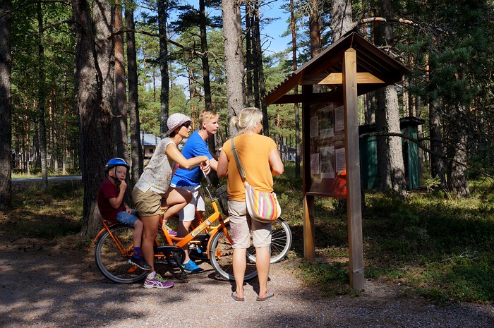 Biking in Hanko in Finland checking out the local signboards for directions in the shade