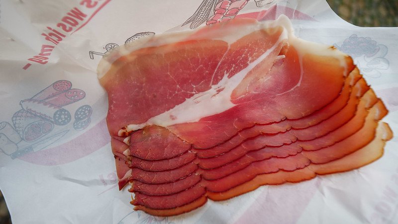 Thin slices of smoky, cured Black Forest ham laid out on deli paper, showcasing its rich marbled texture and deep red colour while sampling local specialties in Freiburg im Breisgau, Germany