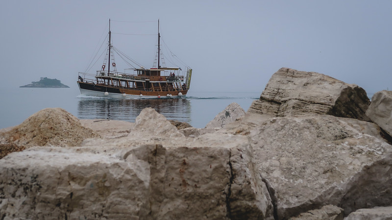 Boat tour from Rovinj in a classic looking traditional vessel as framed by jagged rocks on the shore in Croatia 
