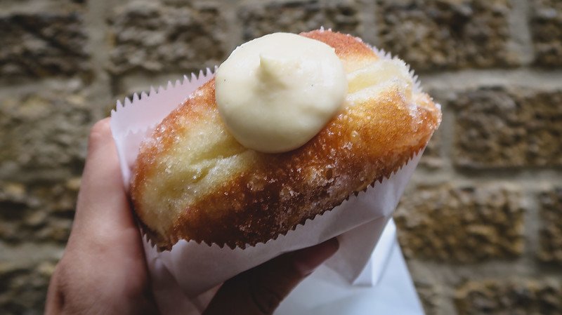 Close-up of a famous Bread Ahead donut from Borough Market in London, filled with rich cream and coated in sugar, a sweet treat that has become a must-try for visitors exploring the city’s vibrant food scene and artisanal bakeries