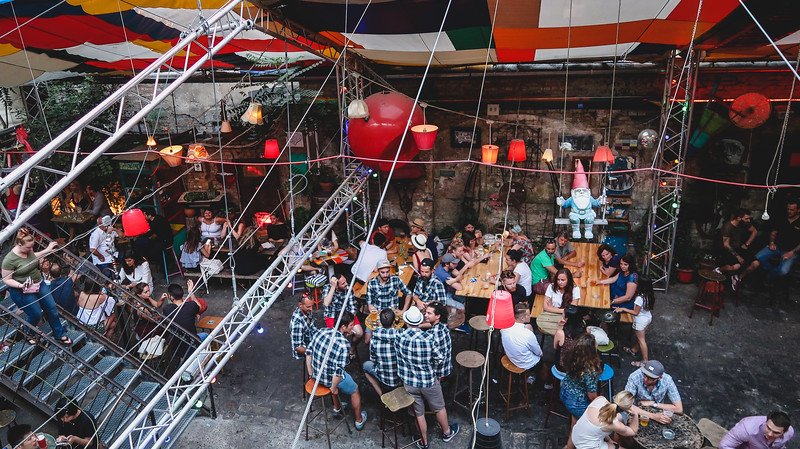 Lively night scene at one of Budapest’s famous ruin bars, with groups of friends drinking, chatting, and enjoying the eclectic décor under colorful canopies. Visiting ruin bars is one of the best things to do in Budapest at night for a unique local experience