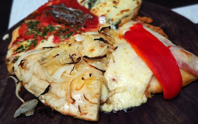 Buenos Aires assorted pizza slices oozing with cheese on a platter in Argentina 
