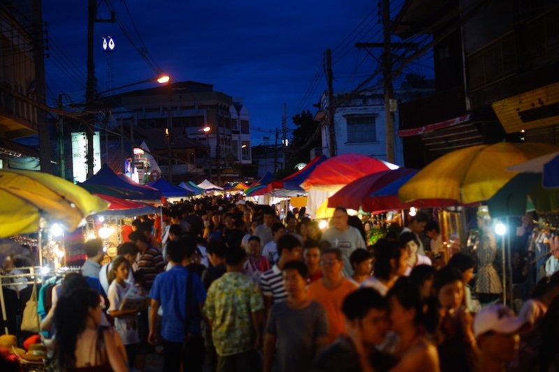 Bustling hive of activity and crowds at the Chiang Mai Saturday Night Market in Thailand with crowds and vendors competing for space 