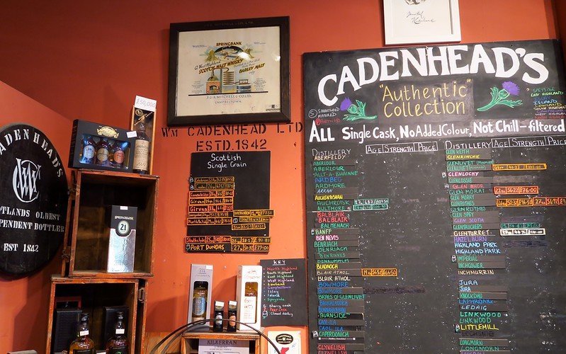 Interior of Cadenhead’s Whisky Shop in Edinburgh, Scotland with chalkboard listing single cask whiskies and bottles on display