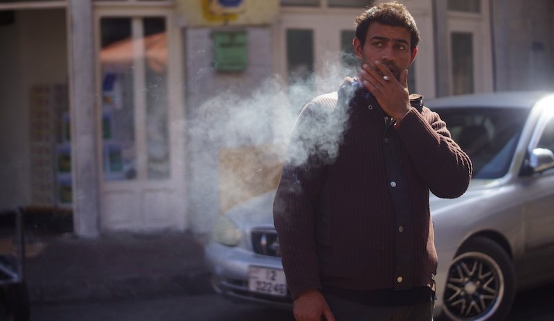 Candid shot of a man smoking and blowing smoke in Amman, Jordan Candid shot of a man smoking and blowing smoke in Amman, Jordan