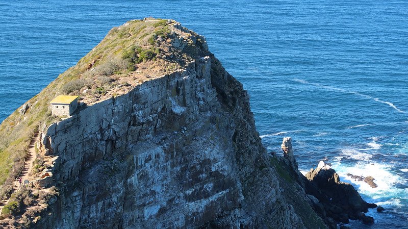 Dramatic view of the rugged cliffs and old lookout structure at Cape Point in Table Mountain National Park, South Africa, surrounded by the deep blue waters of the Atlantic Ocean, captured during a scenic Cape Peninsula sidecar tour