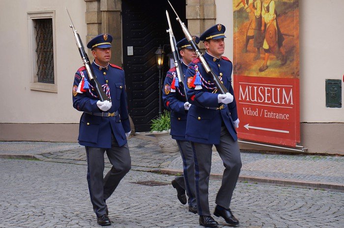 Ceremonial guards in navy blue uniforms and carrying rifles marching during the changing of the guard ceremony at Prague Castle in Prague, Czech Republic