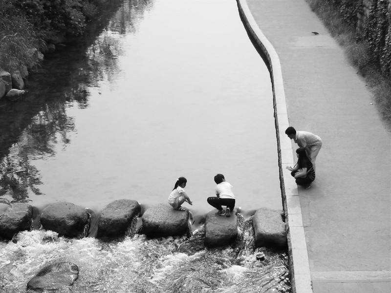Children playing on the Cheonggyecheon River in Seoul, South Korea from a high vantage point greyscale image
