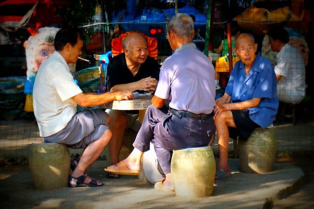 Chinese men playing cards and socializing at the park in Yangshuo, China