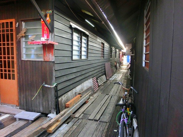 Wooden walkway lined with traditional stilt houses at the Clan Jetties in Georgetown, Penang, Malaysia, with bicycles parked along the side