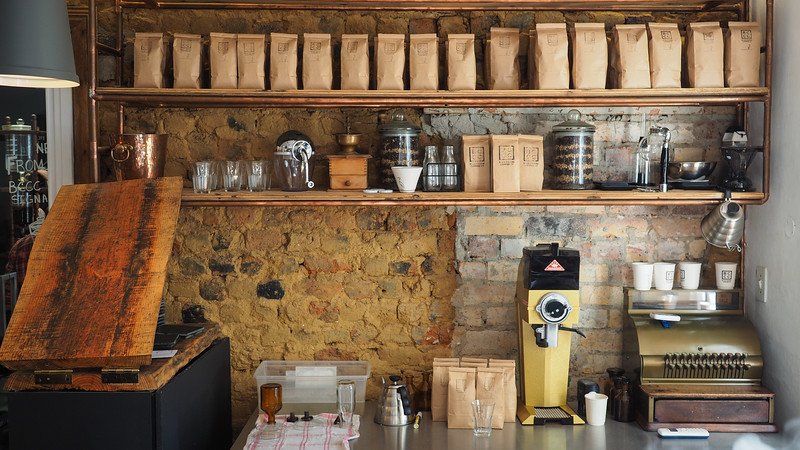 Coffee at BCCC in Stellenbosch with rustic interior views of the brewing area behind the counter and coffee being stored in bags