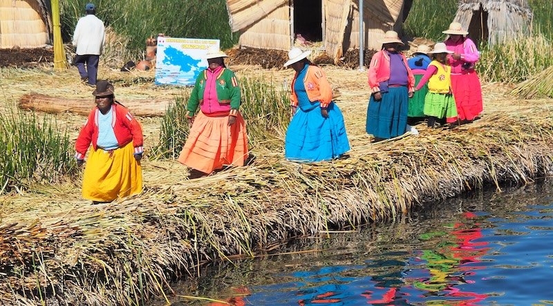 Colorful ladies wearing traditional bright attire waiting to greet us on the floating islands on Lake Titicaca, Peru 