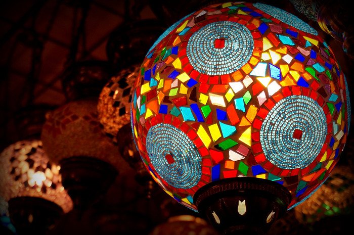 Close-up of a vibrant multicolored glass mosaic lamp glowing warmly at the Grand Bazaar in Istanbul, Turkey, showcasing intricate handcrafted patterns and vivid geometric designs