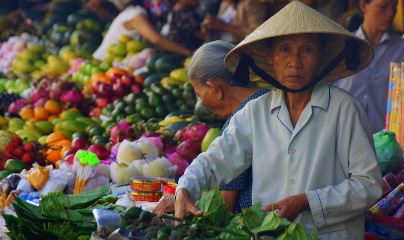 Colorful wet market scene with vendors wearing conical hats in Hoi An, Vietnam 