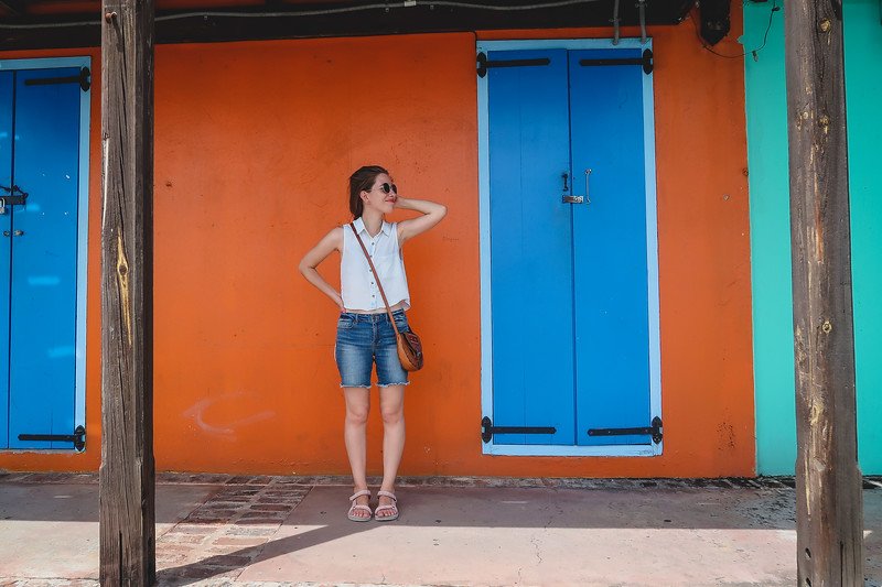Colourful buildings in Antigua with That Backpacker Audrey Bergner posing by a blue door with orange and turquoise walls Colourful buildings in Antigua with That Backpacker Audrey Bergner posing by a blue door with orange and turquoise walls
