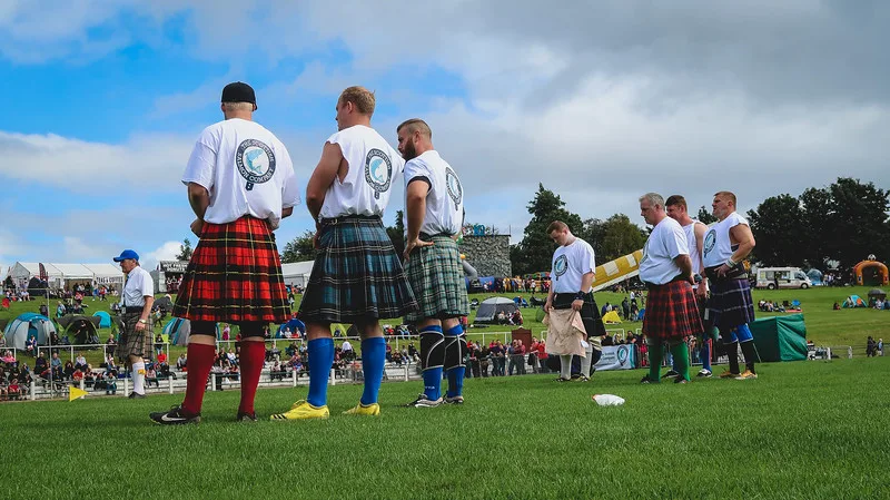 Competitors watching the heavy athletics with men wearing traditional kilts in Dunoon 