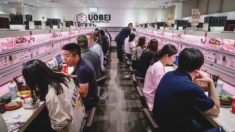 conveyor belt sushi is amazing with a packed restaurant of locals enjoying sushi as a first impressions in Japan