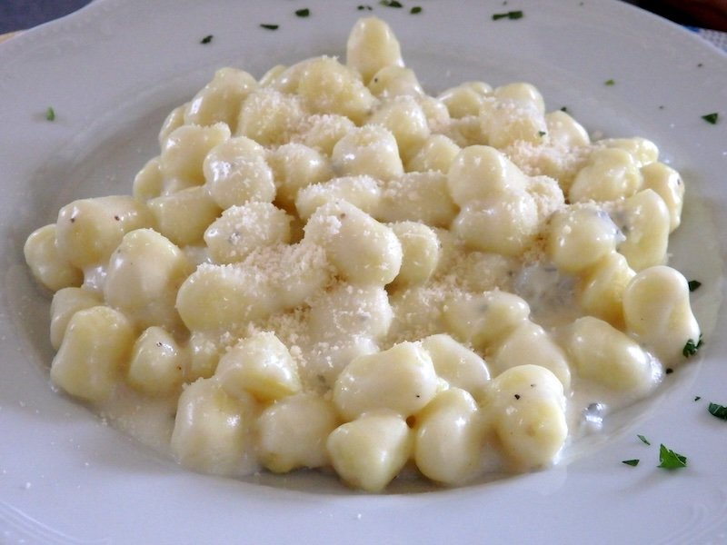 Creamy gnocchi served with a rich cheese sauce and sprinkled with grated Parmesan at a restaurant in Milan, Italy — a classic Italian comfort dish
