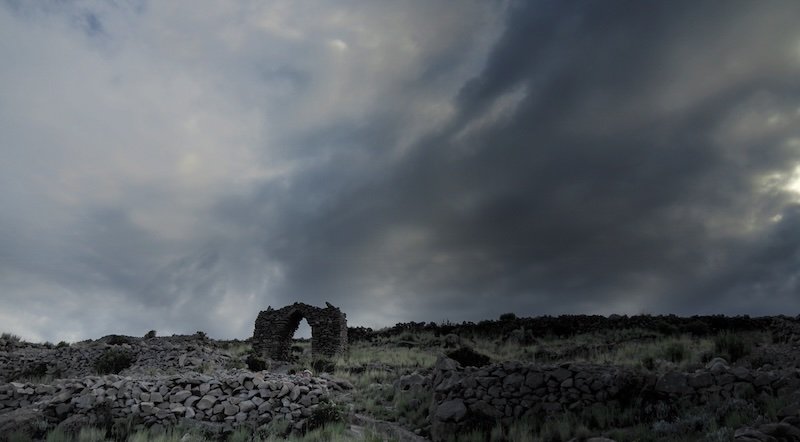 Crumbling archway with moody clouds dominating the rugged scenery in Lake Titicaca, Peru 