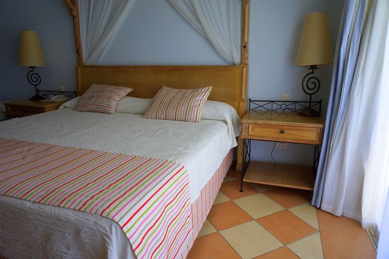 Cozy Cuban resort room with king-sized bed, striped linens, and warm tropical décor during our honeymoon stay in Cayo Santa María