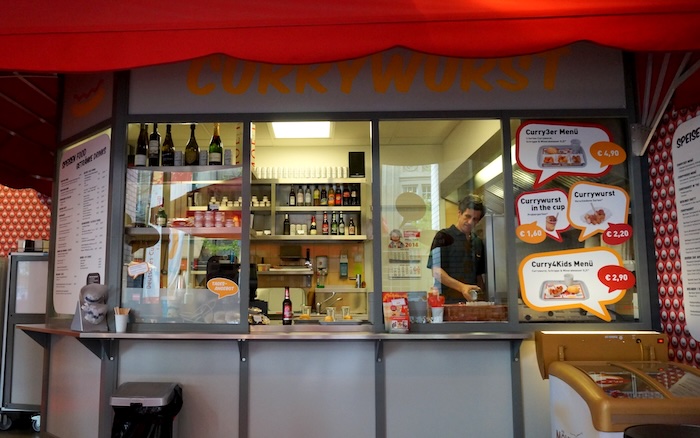 Currywurst street food stall in Berlin, Germany with a vendor making the dish 
