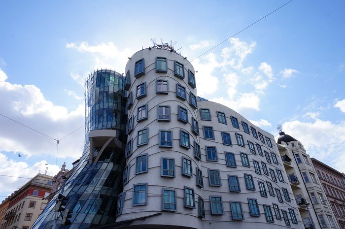 Iconic Dancing House building with its curving deconstructivist architecture and glass tower set against a bright blue sky in Prague, Czech Republic