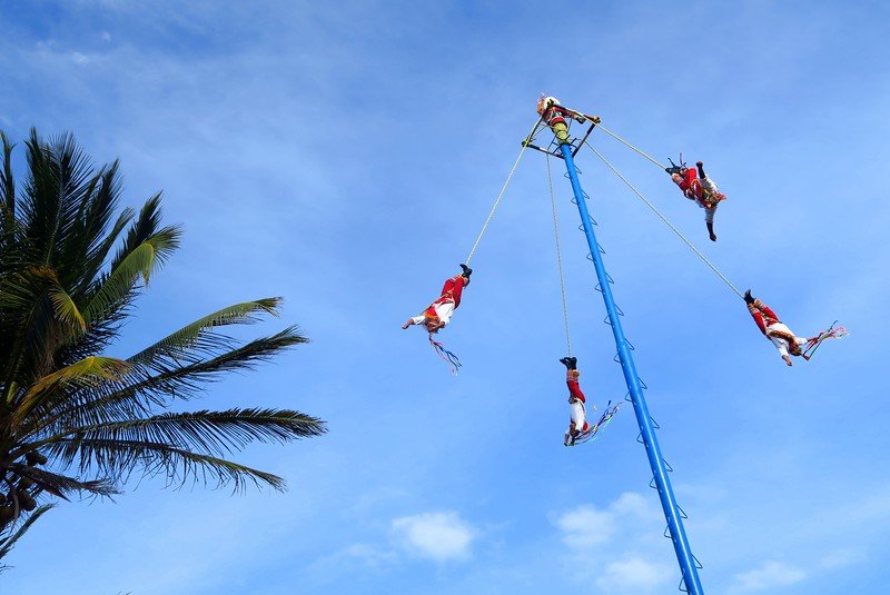 Traditional Danza de los Voladores performance with dancers spinning from a tall pole in Playa del Carmen, Mexico